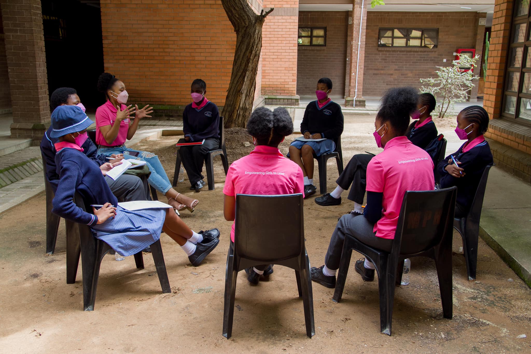 Photo of a G4G mentoring session, there are 8 girls seated in a circle, participating in a facilitated discussion with a mentor