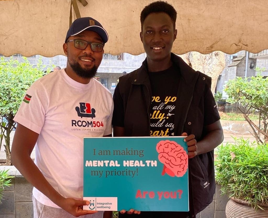 Image of two men standing side by side, holding up a poster that says: "I am making mental health my priority"